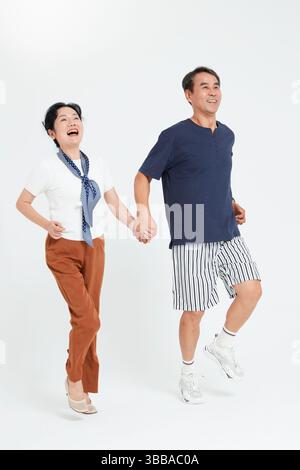 elderly couple running hand in hand​ Stock Photo