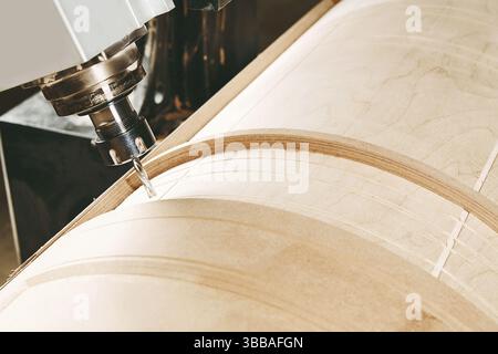 a four-axis numerically controlled woodworking machine cuts out complex lines on the canvas. CNC, computer control. Stock Photo