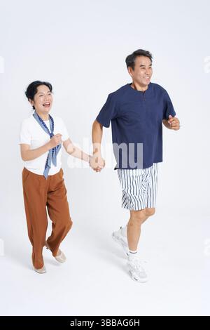 elderly couple running hand in hand​ Stock Photo