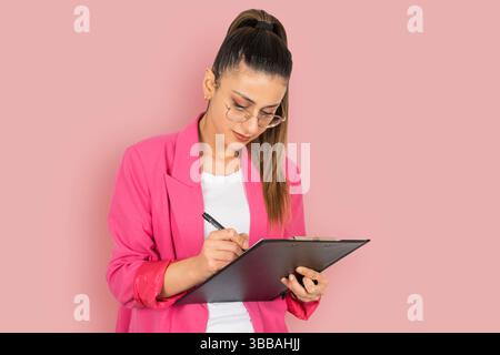 confident serious brunette caucasian business employee woman holding clipboard and pen. Taking notes, working on serious. Successful career concept Stock Photo