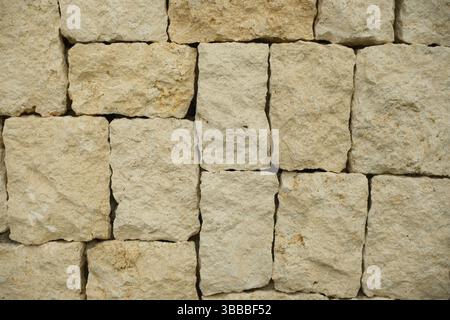 A close up view of a textured rectangular limestone block stone wall Stock Photo
