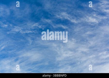 Bright blue sky in the background with wispy white clouds in the foreground. Stock Photo