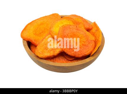 Dried carrot chips in a small wood bowl on a white background side view. Stock Photo