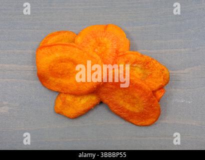 Dried carrot chips on a gray painted background top view. Stock Photo
