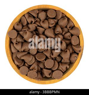 Top view of a wood bowl filled with milk chocolate chips on a white background. Stock Photo