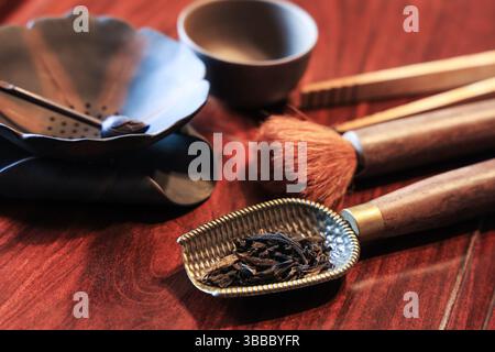 Closeup of oriental tea making ceremony tools: tea spoon, tea brush, tea twezzers, tea cup, tea drippers on a wooden table Stock Photo