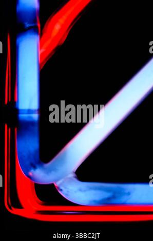 Vertical frame of red and blue neon light pattern with angled tubes on black background Stock Photo
