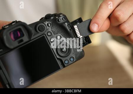 Man inserting SD memory card into photo camera, closeup Stock Photo