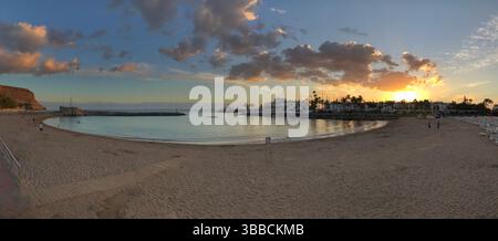 Panoramic view of a serene beach during sunset, showcasing vibrant skies and calm waters. Ideal for backgrounds, headers, and promoting travel or rela Stock Photo