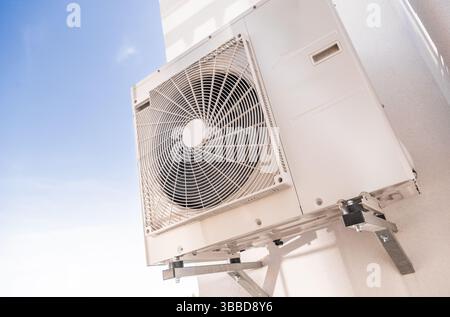 A wall-mounted air conditioning unit is installed securely on an external wall, optimized for cooling efficiency. The fan grill is clearly visible, em Stock Photo