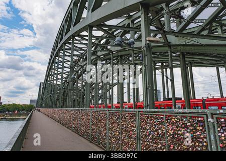 Love locks on Hohenzollern Bridge with red trains and steel arches Stock Photo