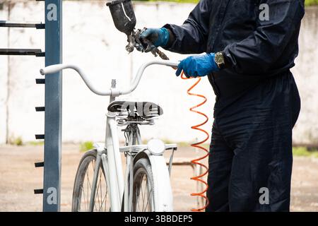 Painting an old bicycle with an airbrush outdoors in white, bicycle restoration, paint Stock Photo
