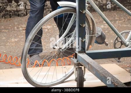 Painting an old bicycle with an airbrush outdoors in white, bicycle restoration, paint Stock Photo