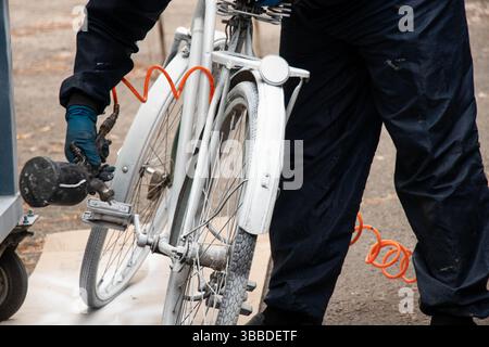 Painting an old bicycle with an airbrush outdoors in white, bicycle restoration, paint Stock Photo