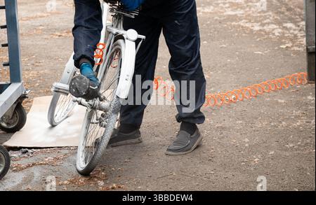 Painting an old bicycle with an airbrush outdoors in white, bicycle restoration, paint Stock Photo