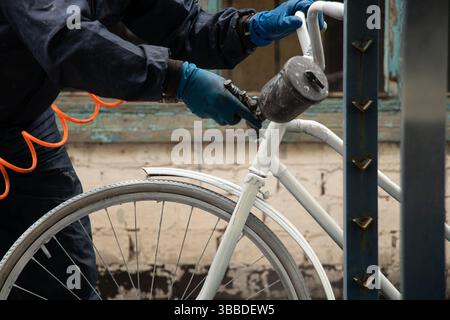 Painting an old bicycle with an airbrush outdoors in white, bicycle restoration, paint Stock Photo