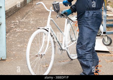 Painting an old bicycle with an airbrush outdoors in white, bicycle restoration, paint Stock Photo