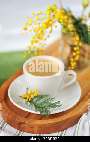 Cup of coffee with mimosa flowers on a wooden tray Stock Photo