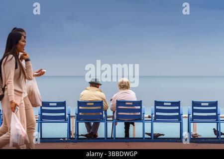 NICE, FRANCE - 02 November, 2018 - Old couple sitting on the bank of the sea, Nice, France Stock Photo