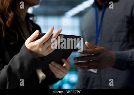 Teamworking data center admins using laptop, conducting security audits, preventing vulnerabilities. Close up of IT staff members using device to review firewall rules, logging incident details Stock Photo