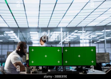 Data center employees using isolated screen multi monitor PC setup to write disaster recovery plans ensuring minimal downtime. Server farm engineers use chroma key computer to monitor performance Stock Photo
