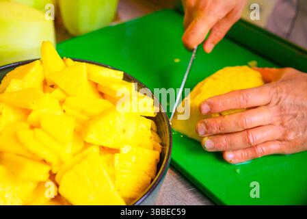 hands of a chef chopping fresh pineapples in a kitchen Stock Photo