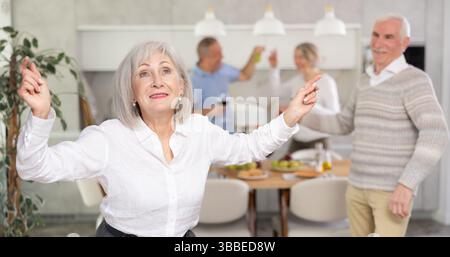 Senior men and women have fun dancing during house party. Stock Photo