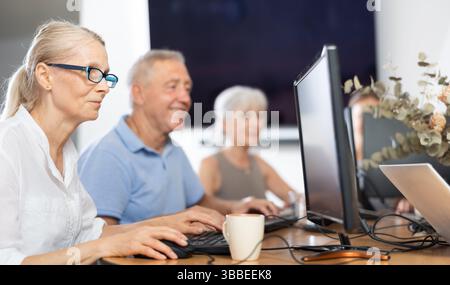 Old woman learning computer programs in training room Stock Photo