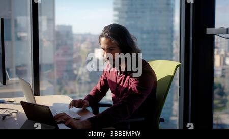 Focused employee working on laptop in modern office Stock Photo