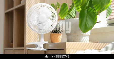Electric fan on commode in living room Stock Photo