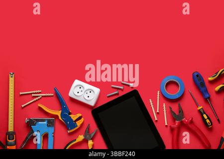 Tablet computer with blank screen and construction tools on red background Stock Photo