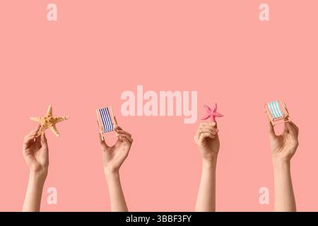 Female hands holding mini deck chairs with starfishes on pink background Stock Photo