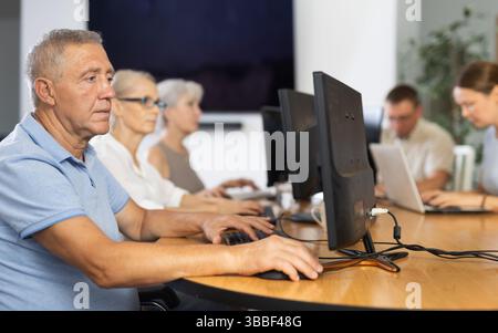 Old man learning computer programs in training room Stock Photo