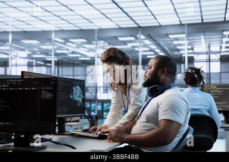 Team of engineers doing brainstorming in server room, implementing power management solutions to reduce energy consumption. Teamworking colleagues integrating new technologies in data center Stock Photo