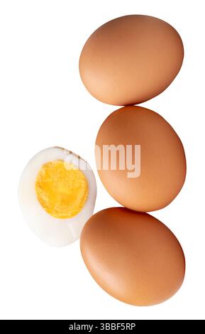 Front view of raw brown chicken eggs and cooked or boiled chicken egg with egg yolk in half in stack is isolated on white background. Stock Photo