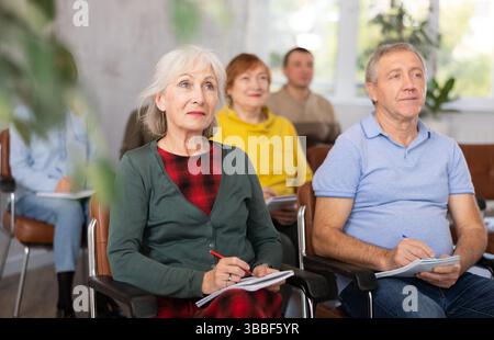 Group of older students sitting and listening at lesson Stock Photo