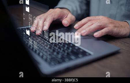 Document Management System concept. A man using DMS software on his laptop to store, share, track and manage files or documents. Stock Photo