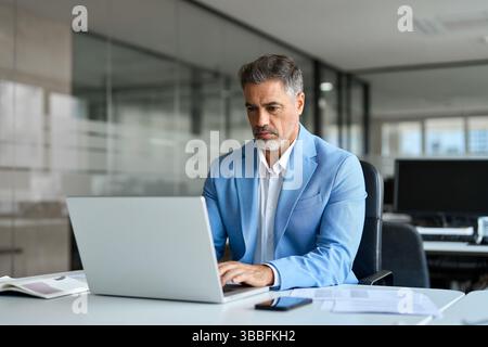 Focused busy middle aged professional business man using laptop in office. Stock Photo