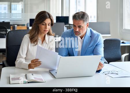 Two executives team working on laptop discussing documents at office meeting. Stock Photo