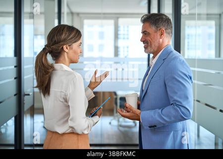 Two busy business people executives team talking walking in office. Stock Photo