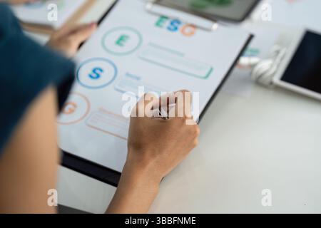 ESG Focus. Individual analyzing Environmental, Social, and Governance metrics on a clipboard. Stock Photo