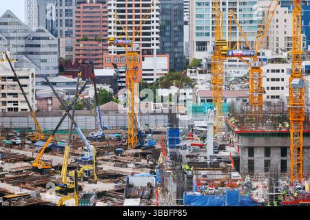 Bangkok, Thailand - April 28, 2025 : urban construction site with cranes, machinery, and workers actively building high-rise structures surrounded by Stock Photo