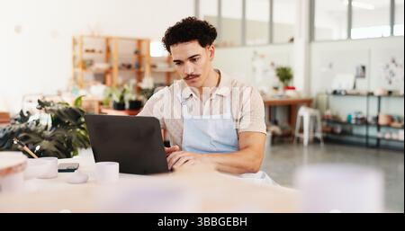 Pottery, creative and man in studio on laptop for inventory, logistics and art checklist of ceramic designs. Business, workshop and person on computer Stock Photo