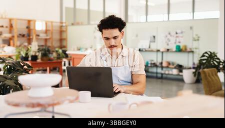 Pottery, creative and man in workshop on laptop for inventory, logistics and checklist of ceramic designs. Business, art studio and person on computer Stock Photo