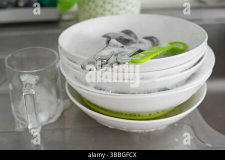 Sink with dirty dishes in kitchen, pile of unwashed plate Stock Photo