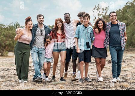 Group of friends of different ages and backgrounds walking together in nature, enjoying a day outdoors with smiles and laughter. Concept of friendship Stock Photo