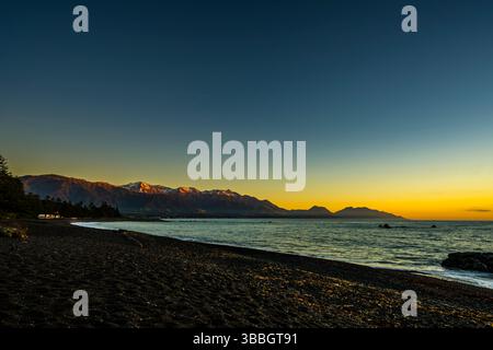Orange glow on the mountains just before sunrise at Kaikoura beach, South Island, New Zealand Stock Photo