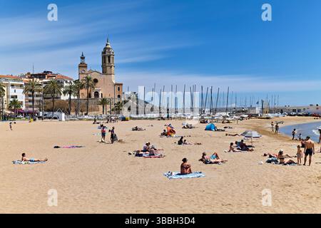 Sitges Catalunya Spain. Sunny beach day with people relaxing and a historic church in the background Stock Photo
