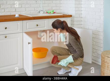 Kitchen sink clogged, woman having household problem, pipes blockages, need plumber service  Stock Photo