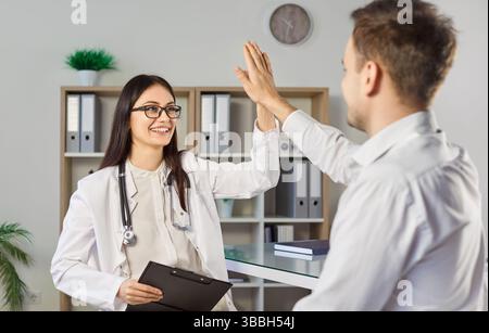 Happy friendly woman doctor giving high five to man patient Stock Photo